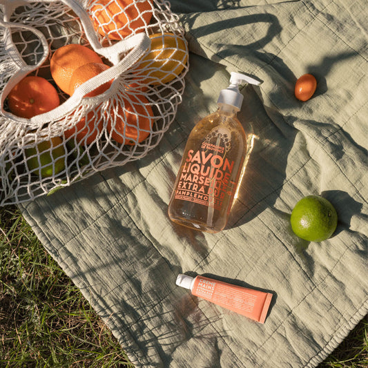 Compagnie de Provence Pink Grapefruit 495 ml liquid soap beside a basket of grapefruit