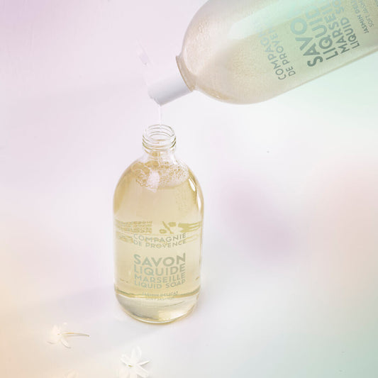 Compagnie de Provence jasmine liquid soap refill pouring into a glass pump bottle