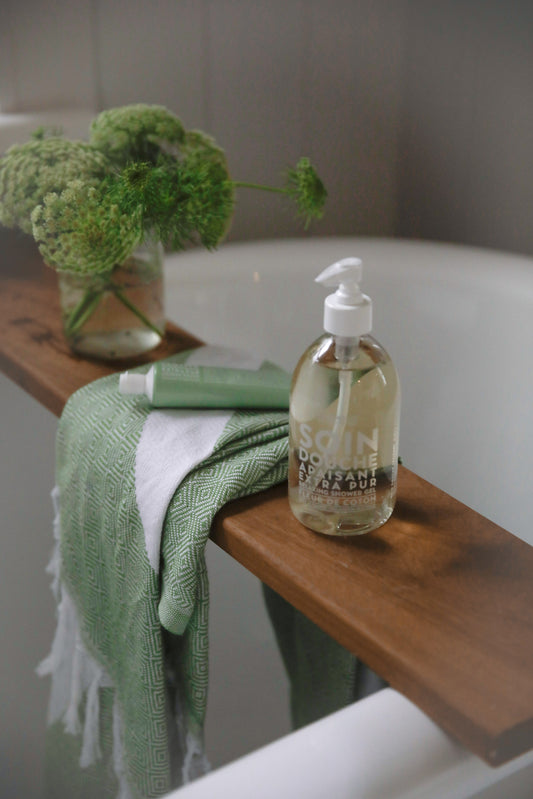 Compagnie de Provence Cotton Flower bottle on a wooden bath board with a green towel
