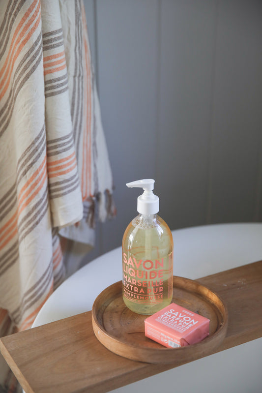 Compagnie de Provence Wild Rose liquid soap and soap bar on a wooden bath board